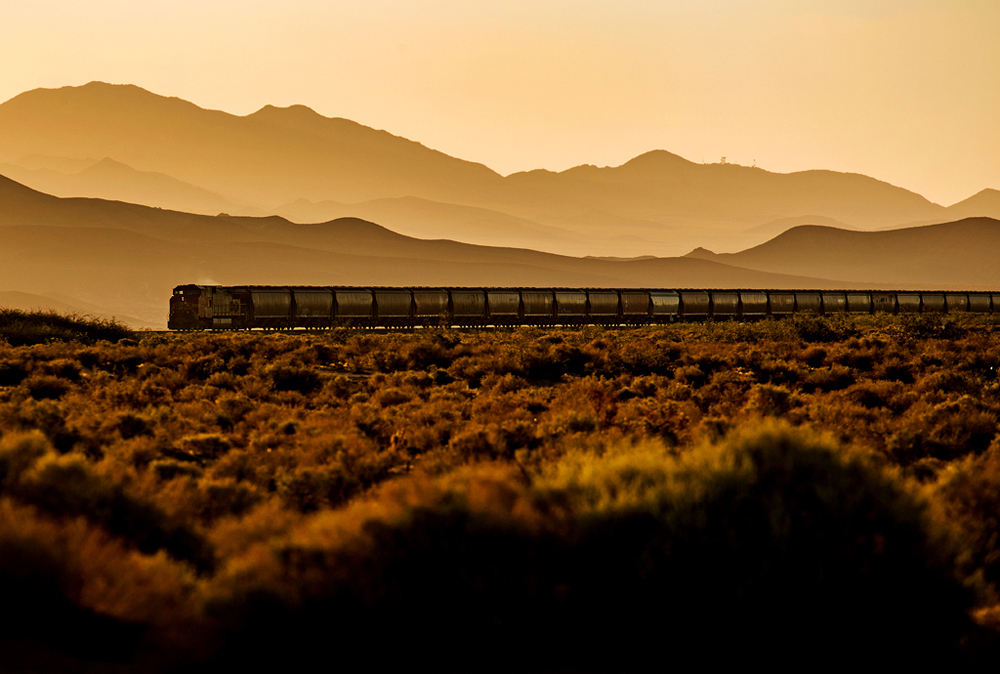 Train in distance in desert landscape near sunset