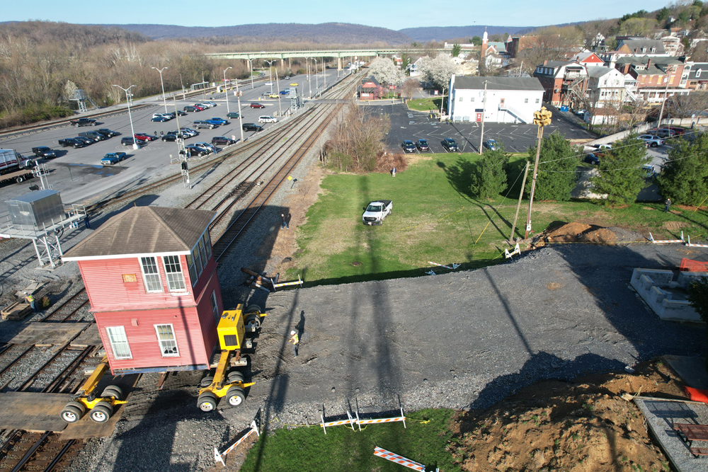 Aerial view of interlocking tower being moved across railroad tracks and uphill