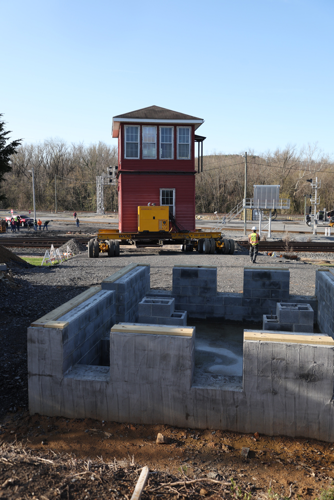 Interlocking tower being moved toward new concrete foundation in foreground