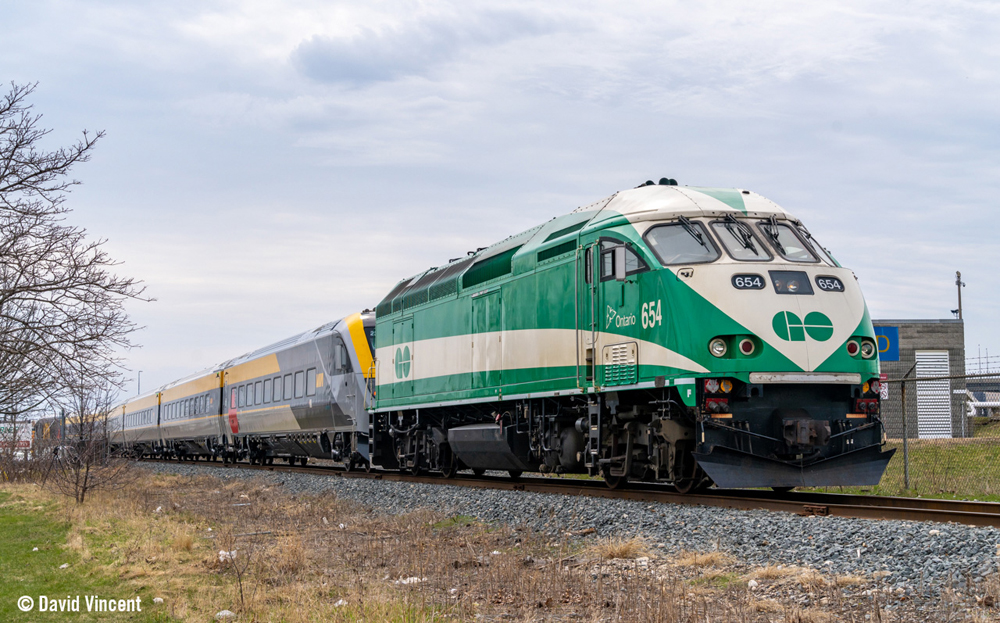 Green and white locomotive pulling passenger train