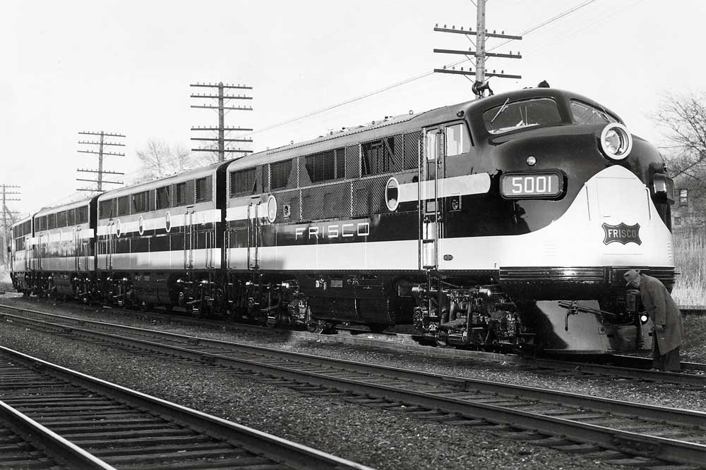 Man inspects front of four-unit streamlined diesel locomotive set