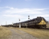 Black and gold diesel locomotives with Frisco freight train between signals