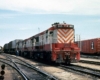 Three red and white diesel locomotives on a Frisco freight train with trailers on flatcars in a yard