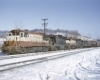 Two red and white and two black and yellow diesel locomotives on a freight train in snow