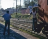 Man prepares to catch papers hung out by man on passing freight train caboose