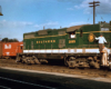 Green and white locomotive with railroad workers on the front.