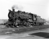 Steam locomotive switch engine in a rail yard.