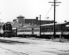 Steamlined locomotive with short passenger train at a station.