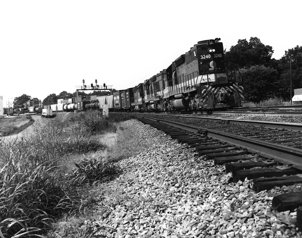 Low-angle image of a black diesel locomotive leading a freight train on a curve.