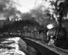 Heavy steam locomotive with freight train in the mountains surounded by trace amounts of snow.