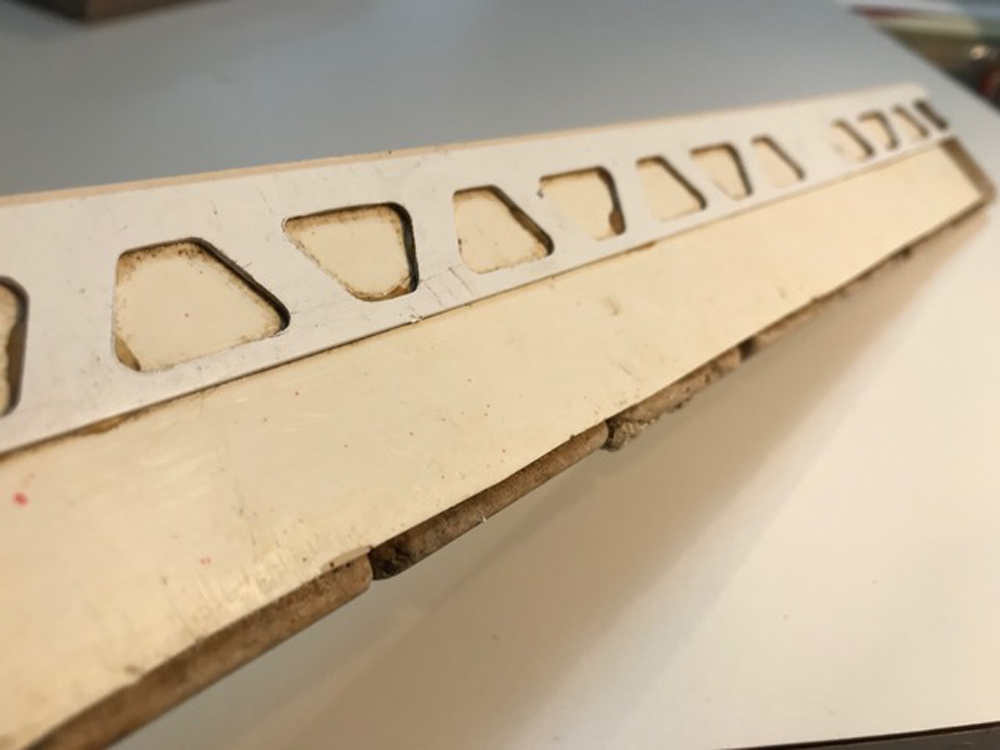 Hand showing the underside of a section of “paved” sidewalks for a garden railway