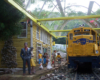 Model diesel locomotive pulls up to a model station with figures