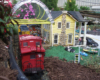 Model train caboose with yellow structure on a garden railway