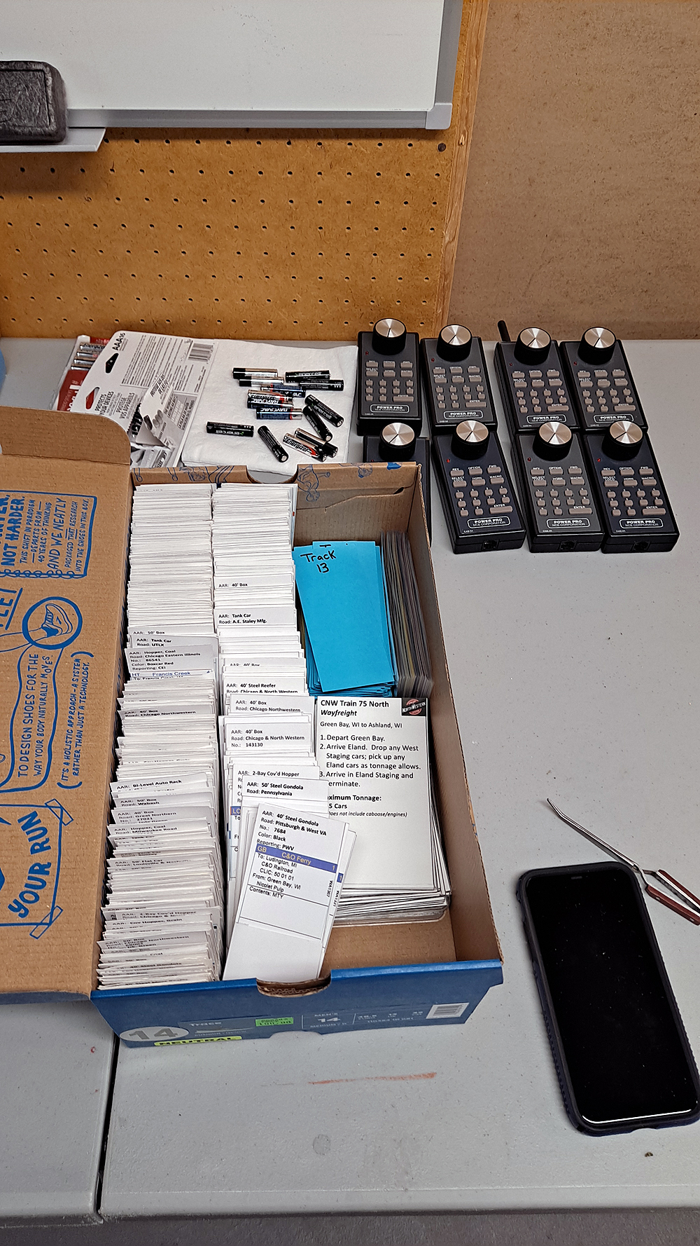 Packing up a model train layout: NCE utility cabs are organized on a table along with a shoebox full of car cards for operation.