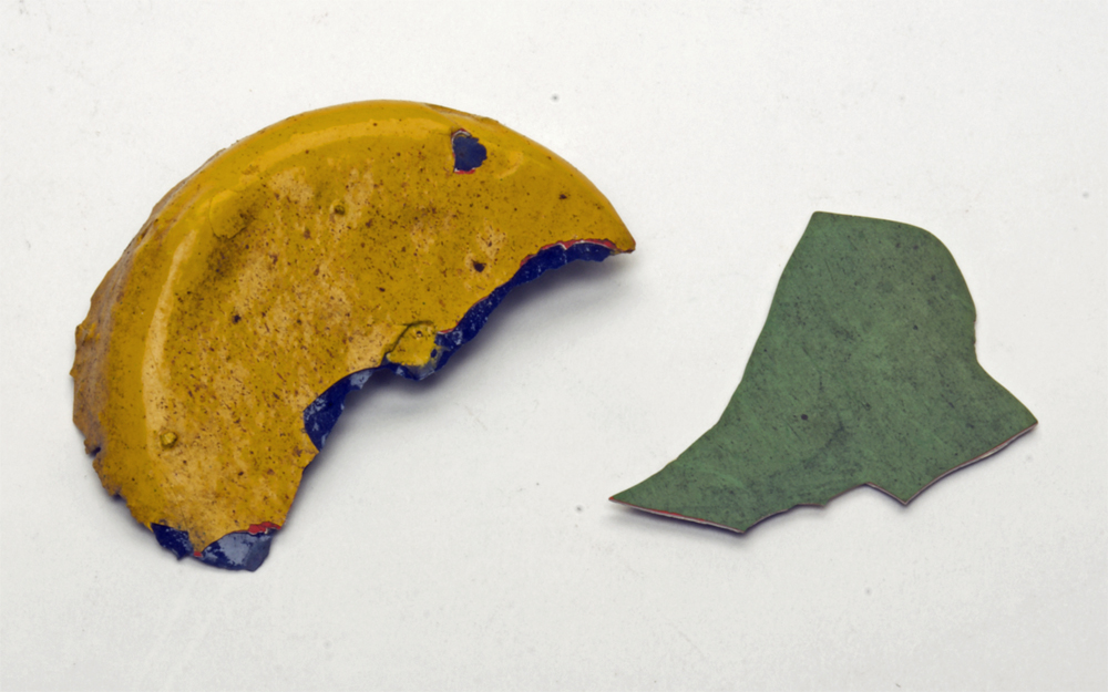 Photo of green and yellow paint chips on white background.