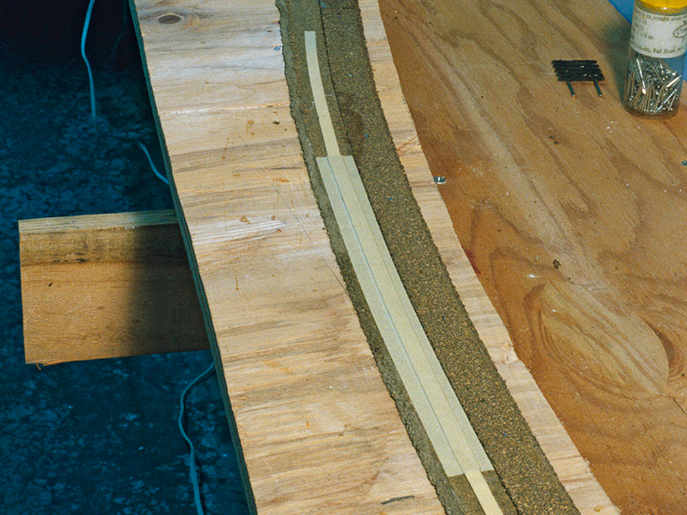 A superelevation ramp made of cardstock and masking tape strips is taped to the outside of a curve of cork roadbed