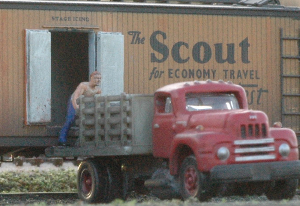 Model figure unloading truck on a model railroad