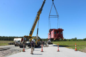 crane lifts red railcar