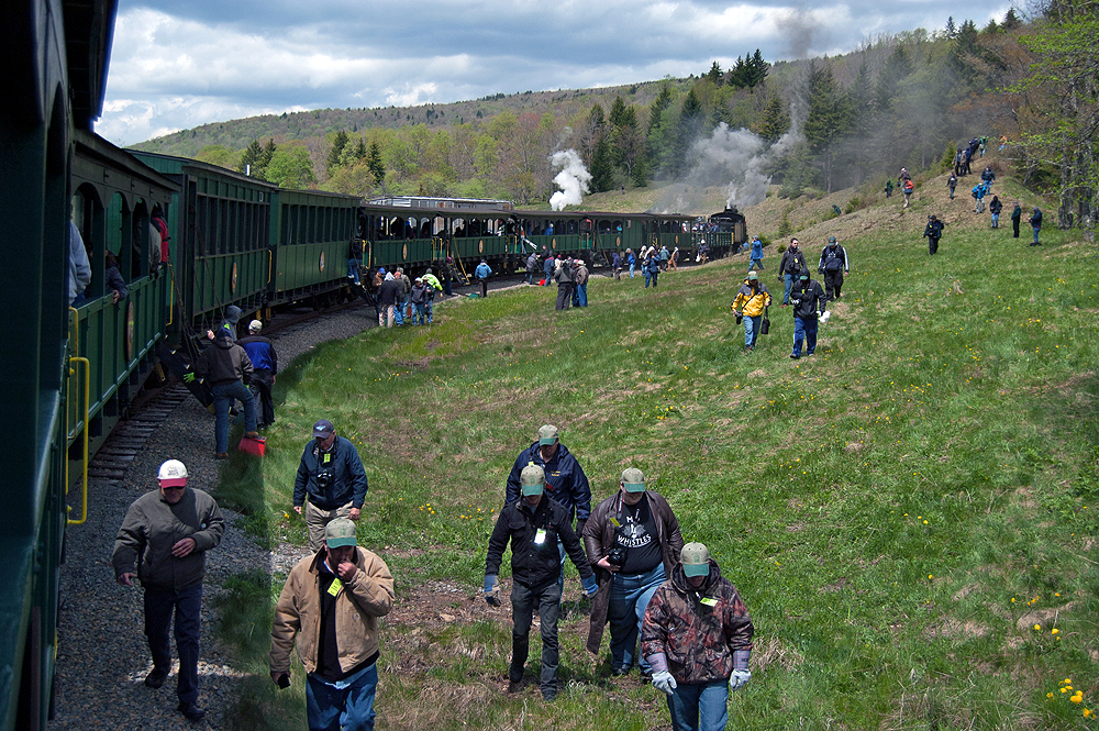 A long green passenger train stopped to let railroad photographers on board.