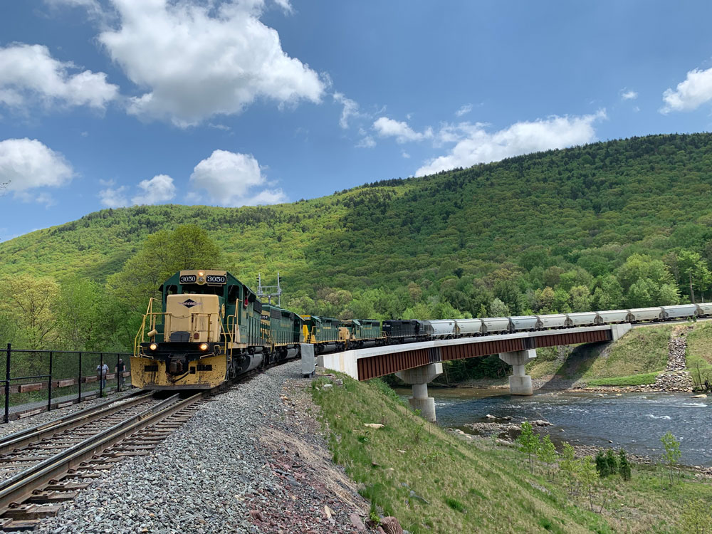 blue and yellow locomotive moves train of frac sand railcars