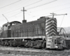 Black and white switcher locomotive with trolley pole.