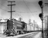 Baldwin locomotive with trolley pole extended pulling refrigerated boxcars.