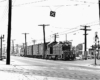 EMD locomotive with trolley pole extended pulling a freight train.