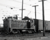 EMD locomotive with trolley pole extended pulling boxcars.