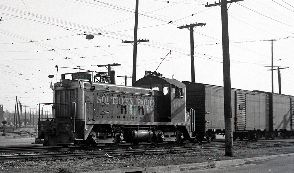 EMD locomotive with trolley pole extended pulling boxcars.