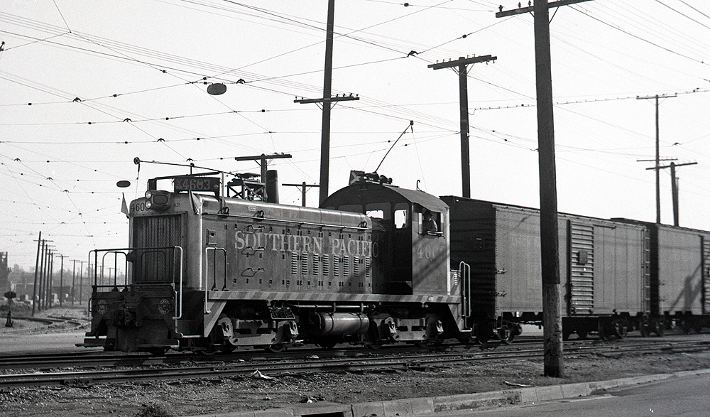 EMD locomotive with extended carriage mast pulling boxcars.