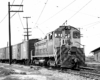 EMD locomotive with trolley pole extended pulling freight train through switches.