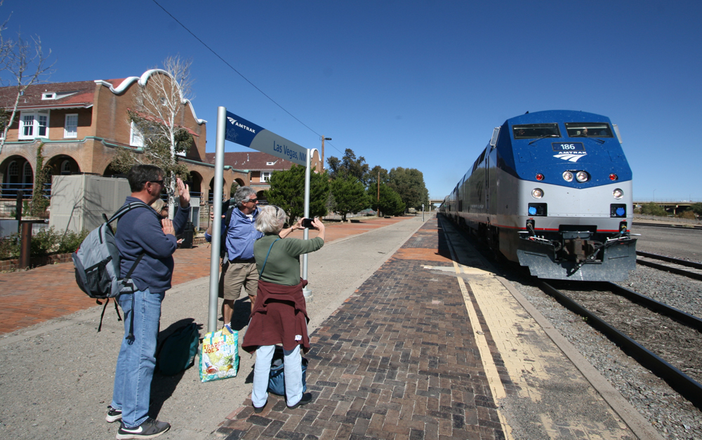 People taking pictures of train arriving at station