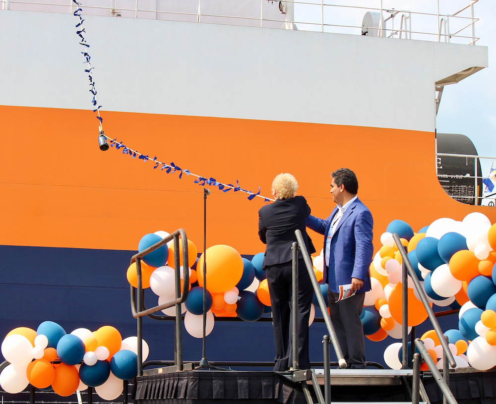 La mujer agita la botella desde la plataforma hasta el barco.