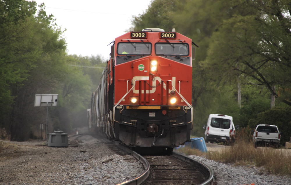 Train with red locomotive approaching curve