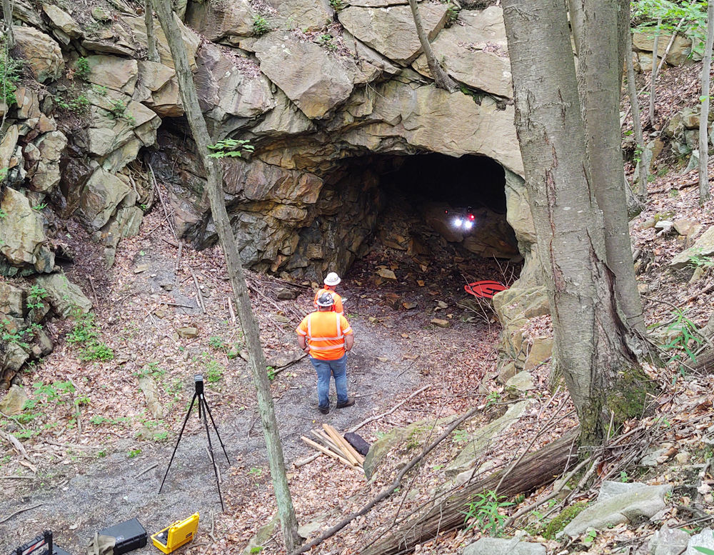 Men standing outside tunnel watching drone at entrance