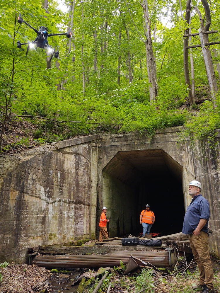 Men standing at tunnel entrance looking at drone in midair