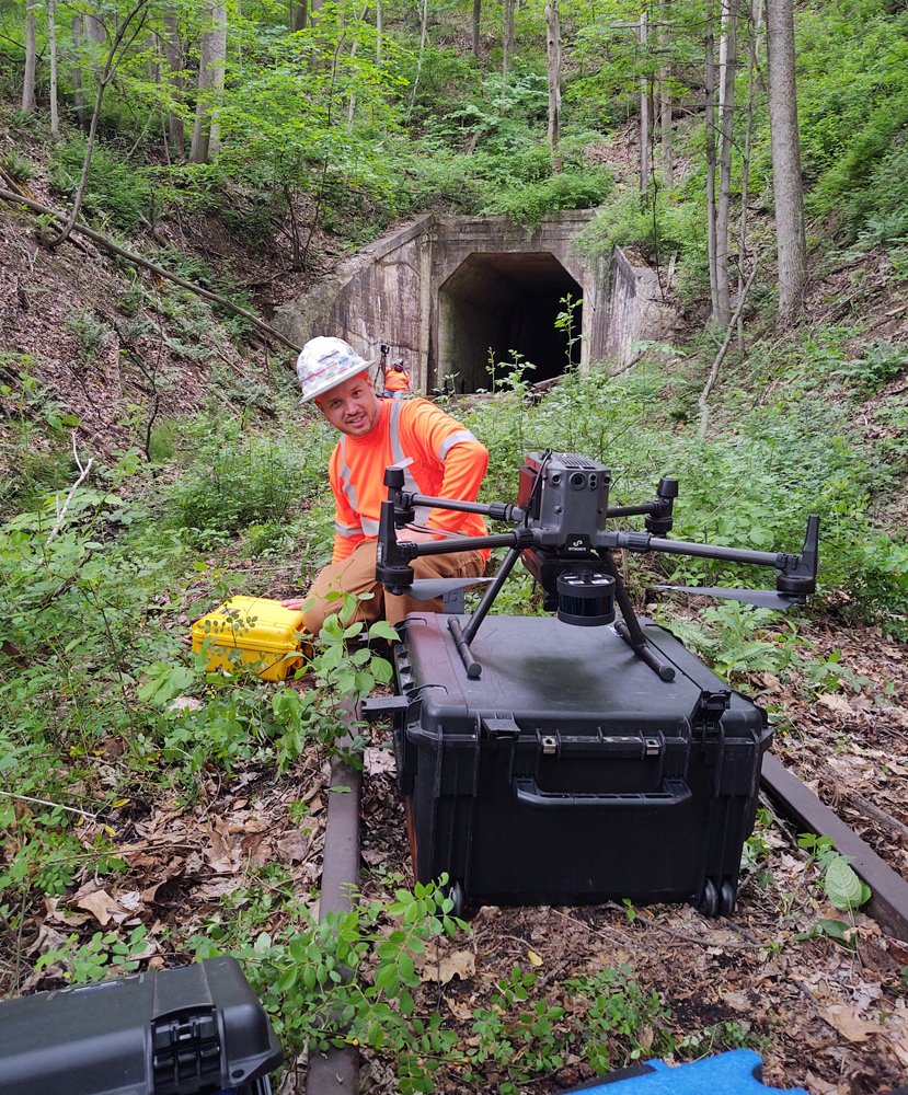 Man in orange high-visibility clothing inspects drone on ground