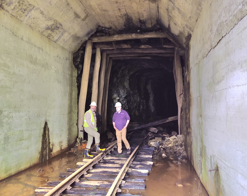 Men standing in tunnel with partial collapse behind them