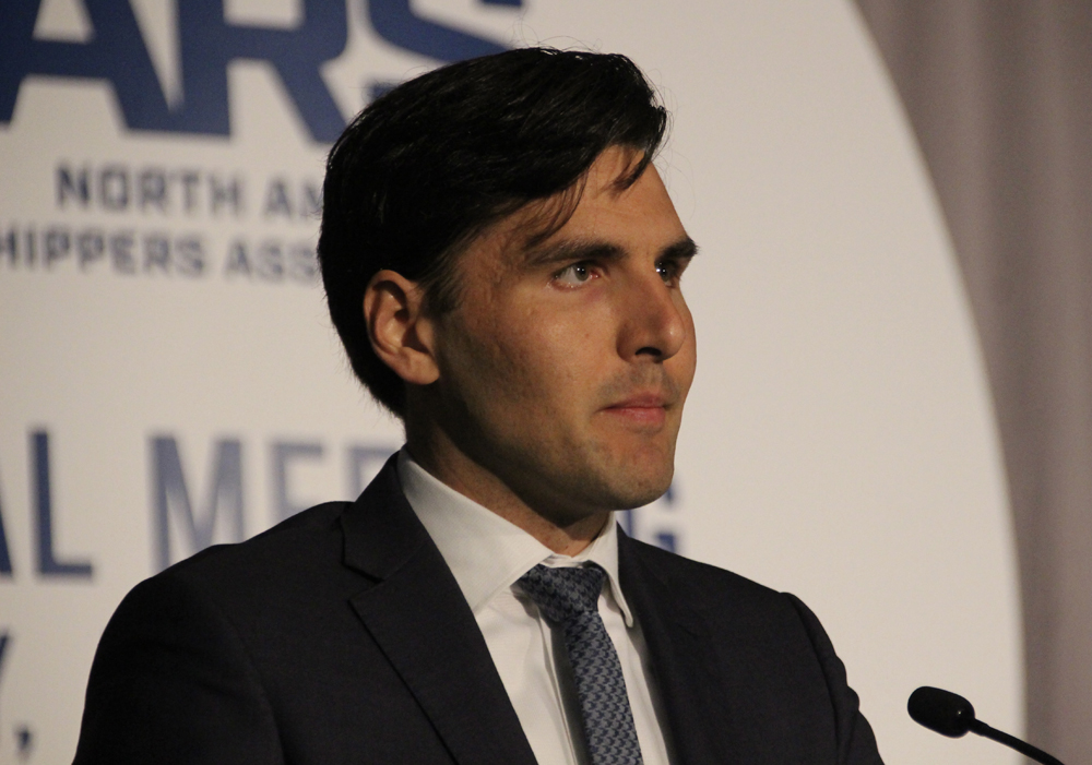 Man in dark suit and tie standing at microphone