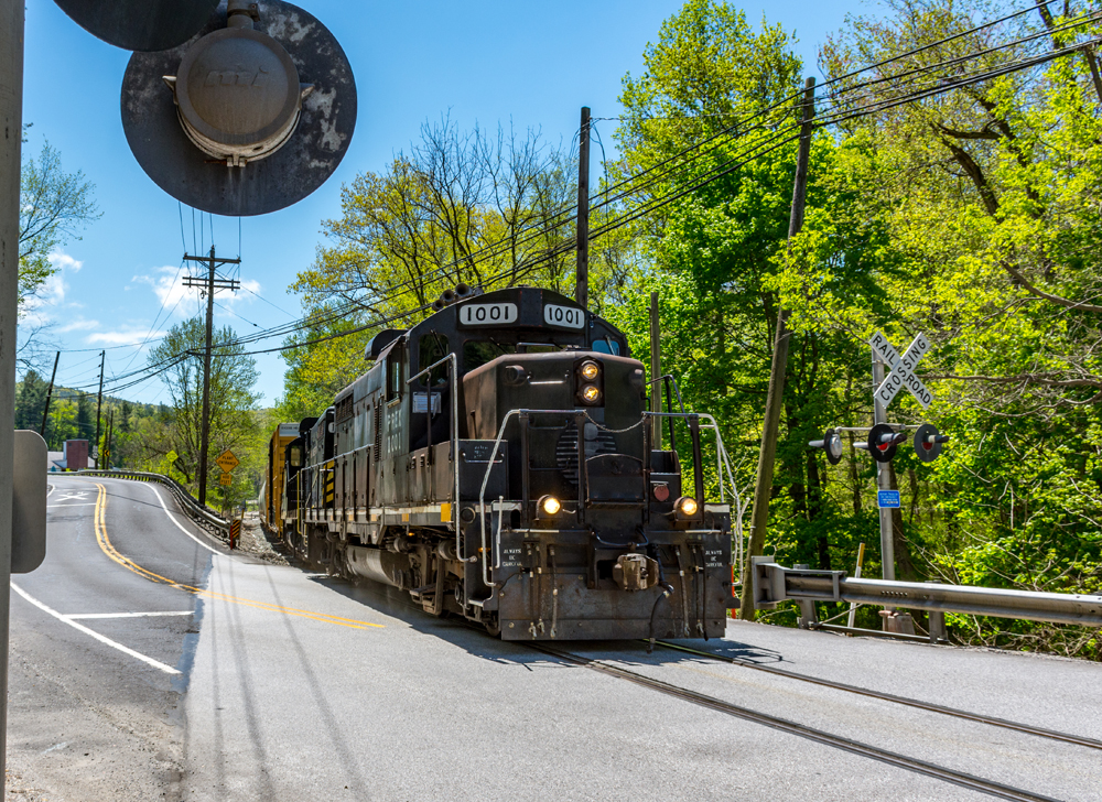 Black locomotive leads train across highway