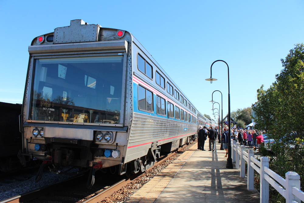 Passenger train with theater car at rear stopped at station