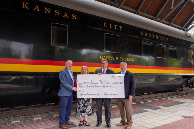 Four people with oversized check standing in front of passenger car with name "Harry Truman"