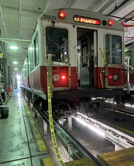 Rapid transit equipment parked over inspection pit in shop building
