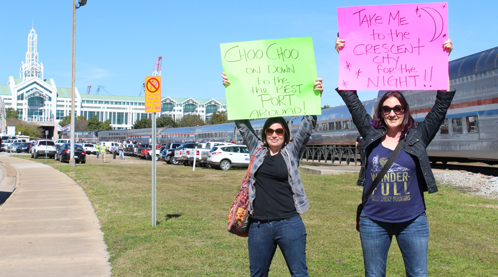 Two women holding signs supporting Gulf Coast Amtrak service