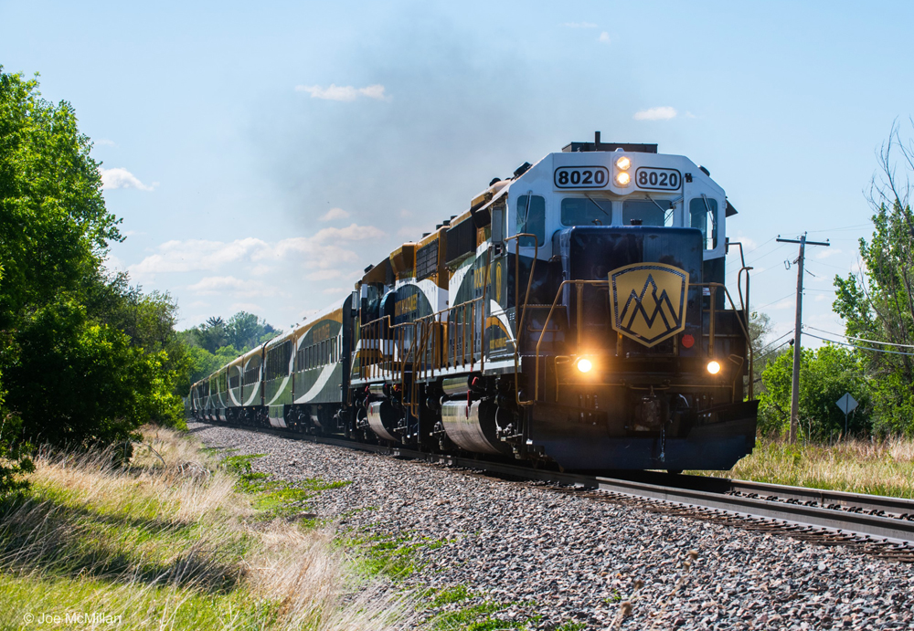Passenger train led by locomotives in matching blue, gold, and white paint scheme