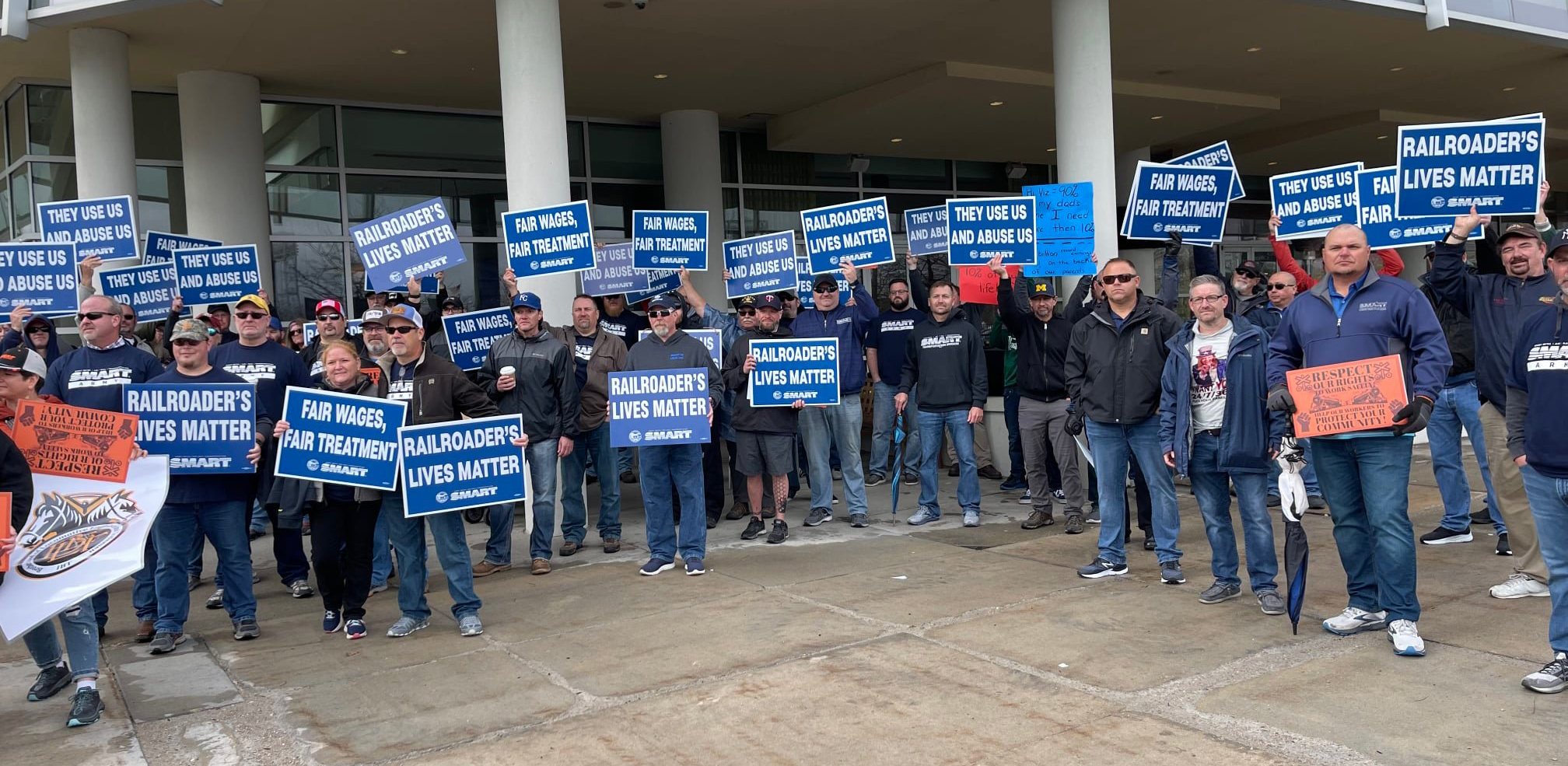 Group of people holding picket signs outside building