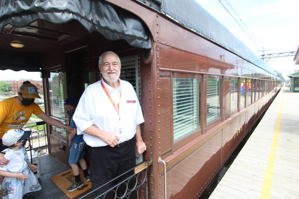 Man standing on platform of Tuscan Red passenger car