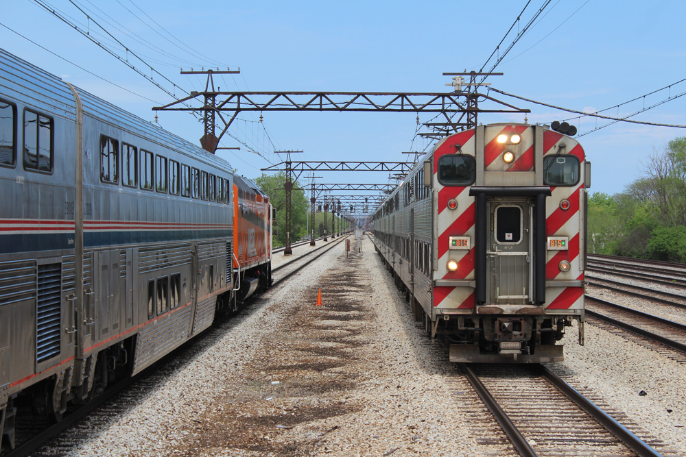 Bilevel electric commuter train passes bilevel passenger cars
