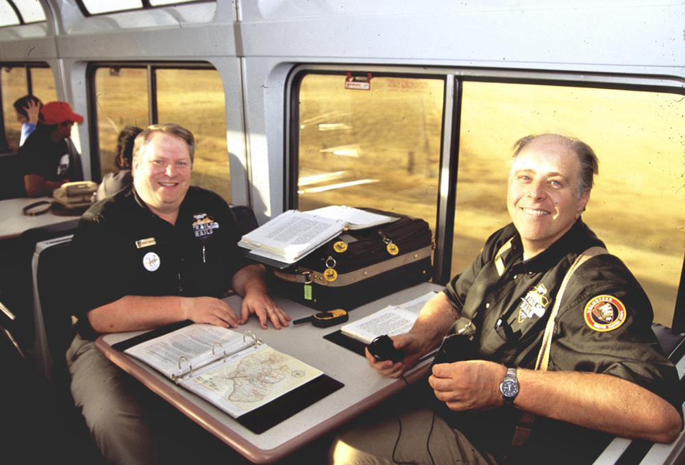 Two men sitting at table in lounge car with various books