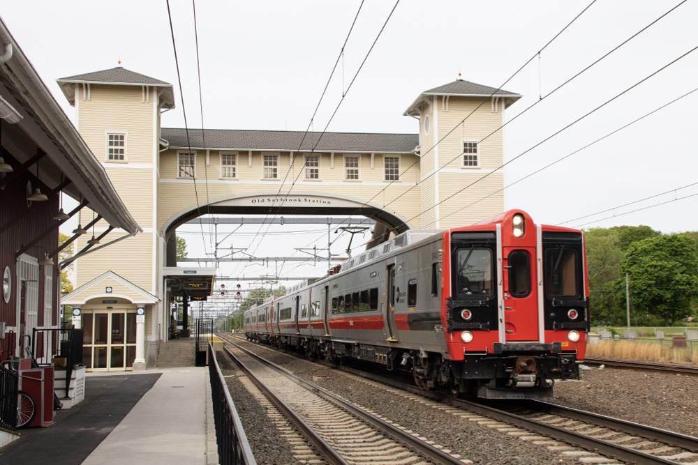 Train pases through station with bridge over tracks